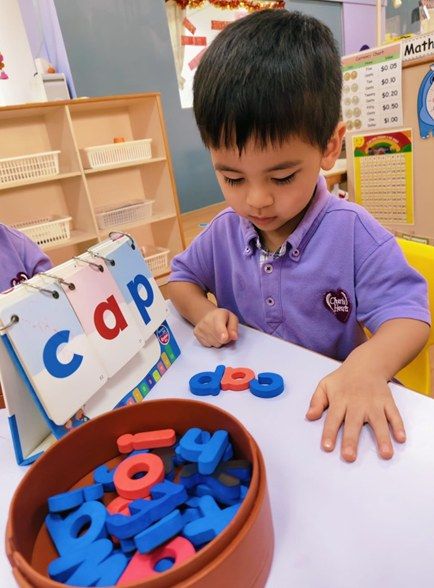 A child arranging alphabet letter tiles at a classroom table