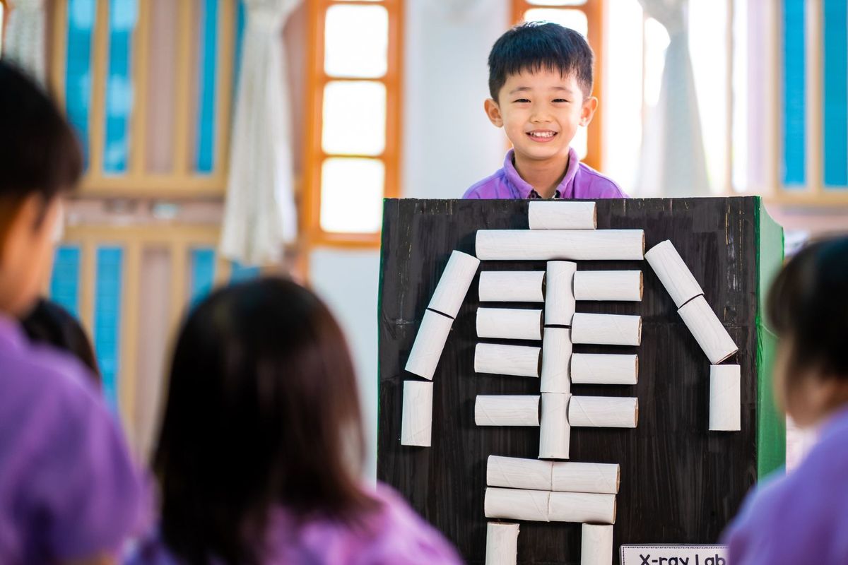 A child presenting a paper craft skeleton project during a STEM activity