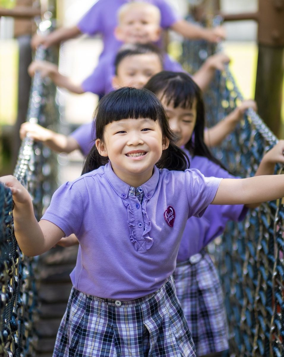 A child exploring the outdoor rope bridge play structure