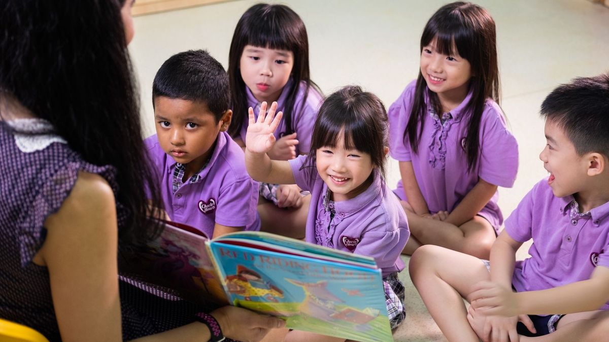 A child smiling during a reading activity with her teacher