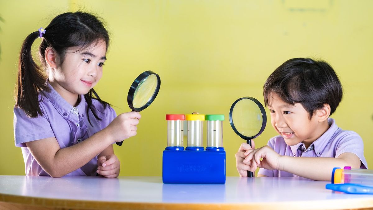 Two children exploring science specimens with magnifying glasses
