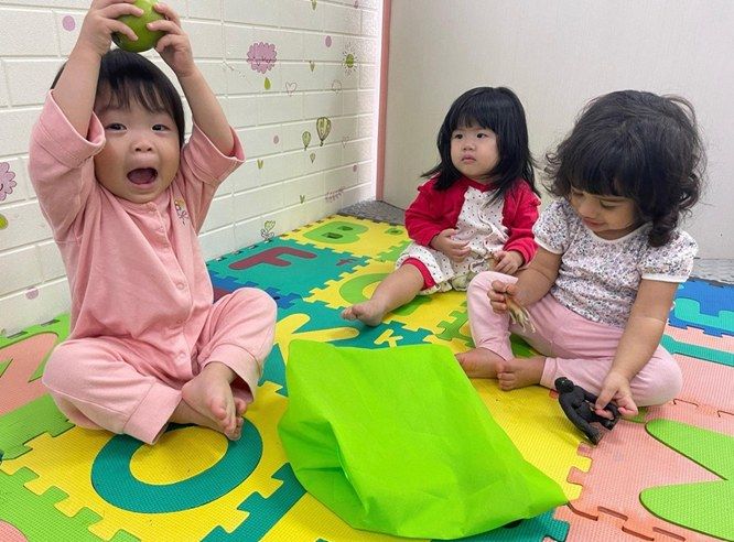 Toddlers playing together with toys on a colourful alphabet mat